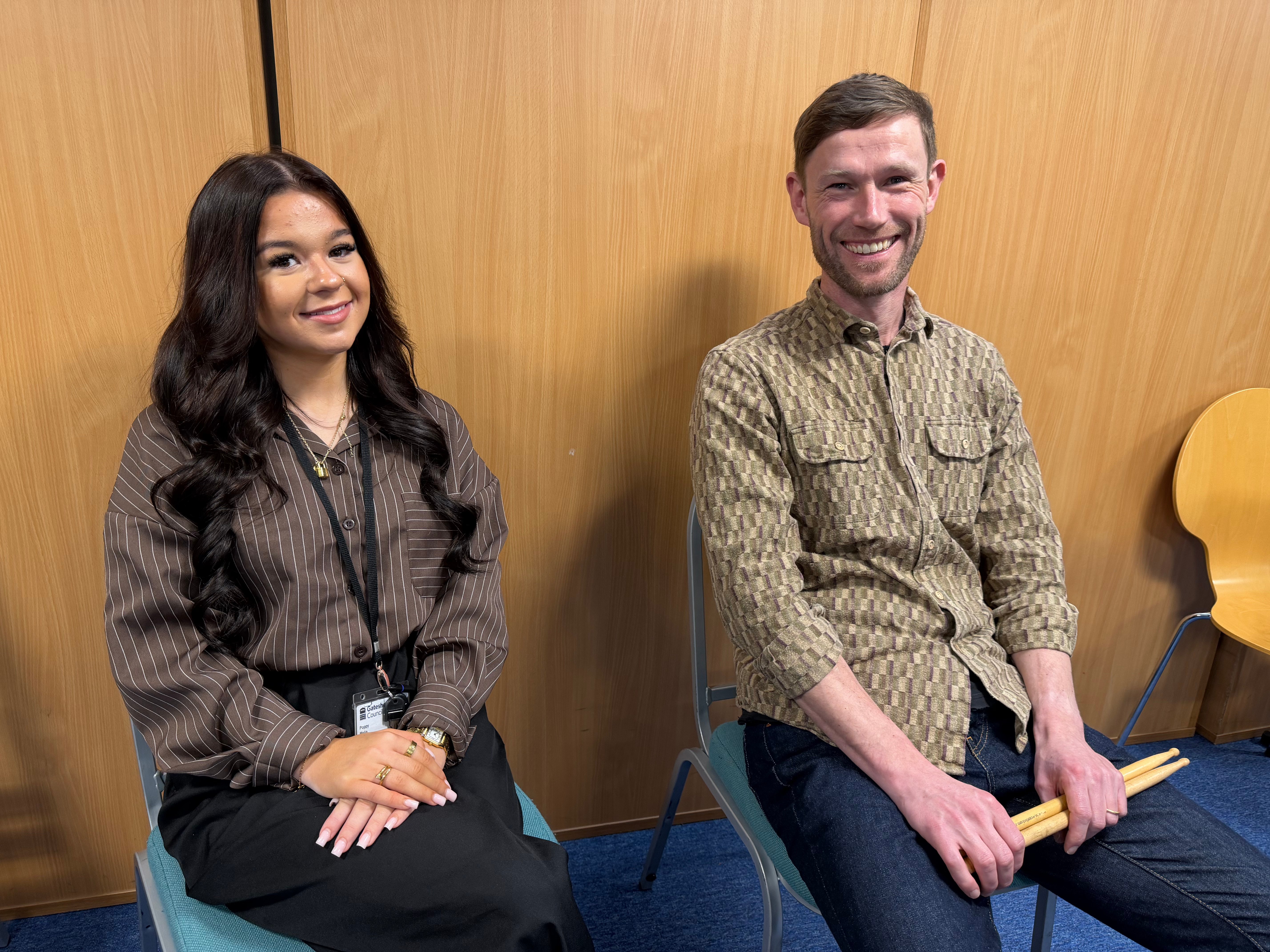 Two apprentices sitting next to eachother, One holding drumsticks, showing the range of career paths available through North East apprenticeships