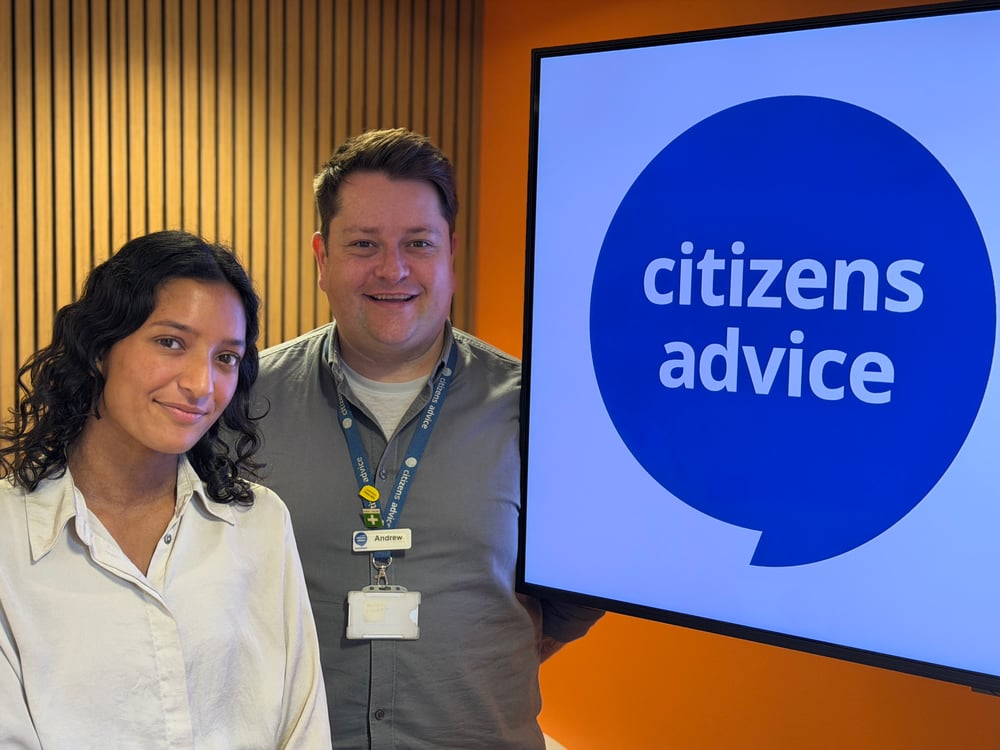 Two people standing beside a Citizens Advice sign